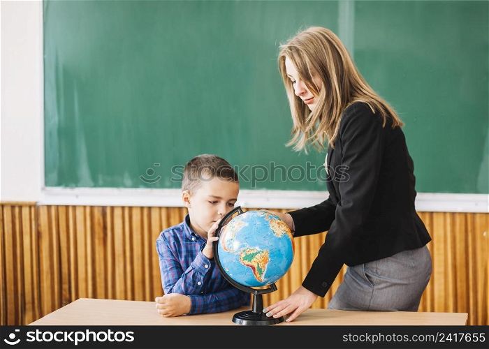 female teacher student boy working with globe