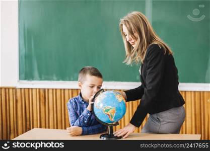 female teacher student boy working with globe