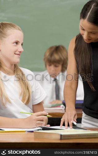 Female teacher teaching a schoolgirl in a classroom