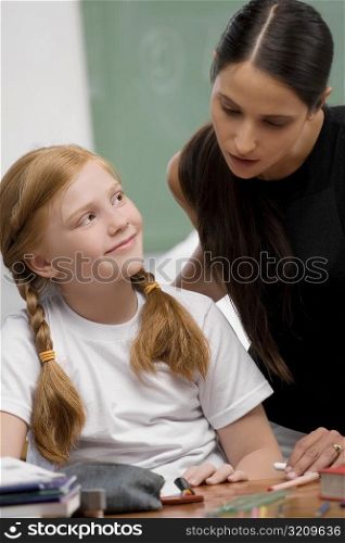 Female teacher teaching a schoolgirl in a classroom