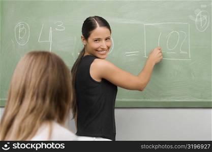Female teacher teaching a schoolgirl in a classroom and smiling
