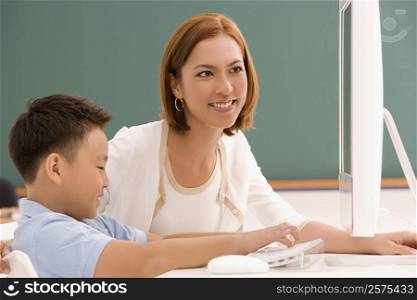 Female teacher with her student in front of a desktop PC