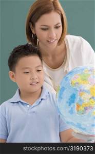 Female teacher with her student looking at a desktop globe