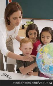 Female teacher with her students looking at a desktop globe