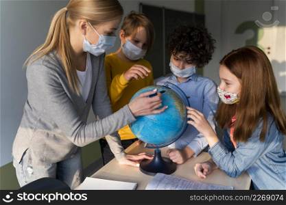 female teacher with medical mask teaching geography with earth globe class