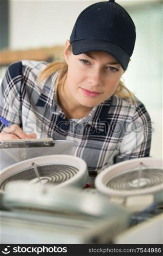female technician checking electric device and taking notes