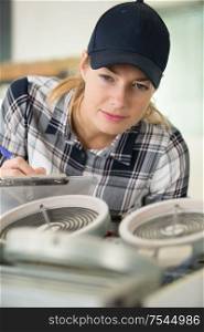 female technician checking electric device and taking notes
