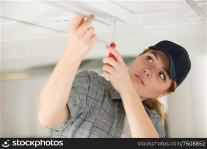 female technician installing a light on the ceiling