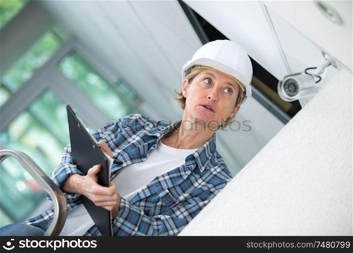 female technician installing camera on wall with screwdriver