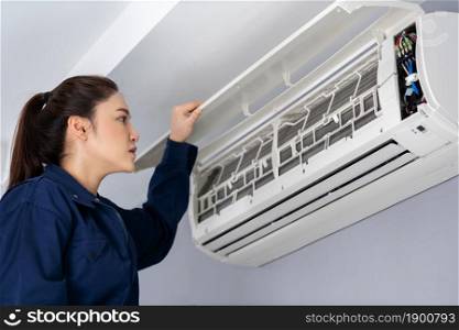 female technician service checking and repairing the air conditioner indoors