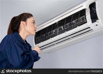female technician service checking and repairing the air conditioner indoors