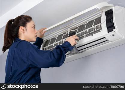 female technician service cleaning the air conditioner indoors