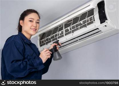 female technician service cleaning the air conditioner indoors