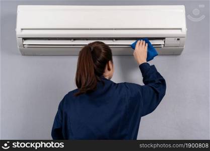 female technician service cleaning the air conditioner with cloth