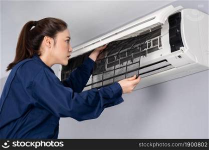 female technician service removing air filter of the air conditioner for cleaning