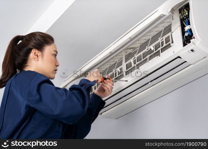 female technician service using screwdriver to repairing the air conditioner indoors