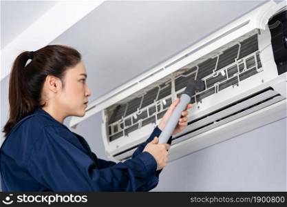 female technician service using vacuum cleaner to cleaning the air conditioner