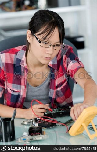 female technician using multimeter for voltage pc measurement