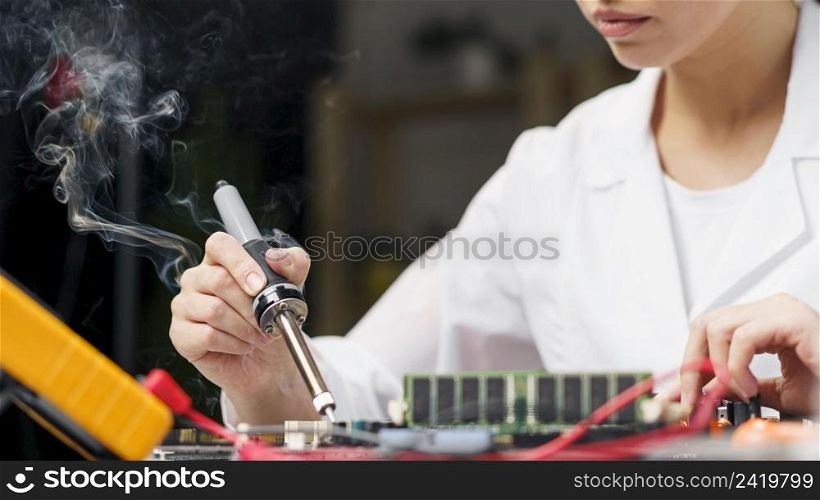 female technician with soldering iron electronics board