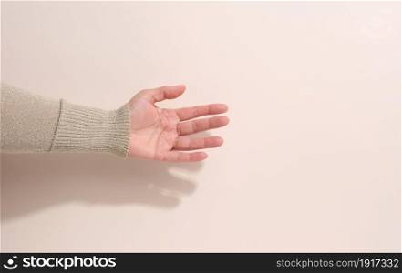 female teen hand to hold something on a beige background. Advertising and product promotion