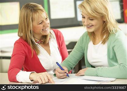Female Teenage Student Studying In Classroom With Teacher