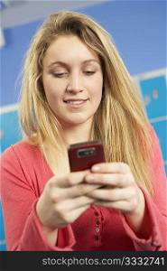 Female Teenage Student Using Mobile Phone By Lockers In School