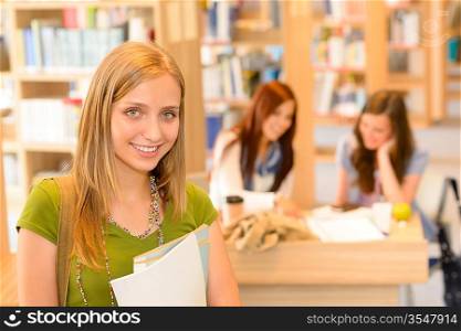 Female teenager student in green top standing at high-school library