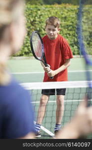 Female Tennis Coach Giving Lesson To Boy