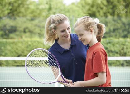 Female Tennis Coach Giving Lesson To Girl