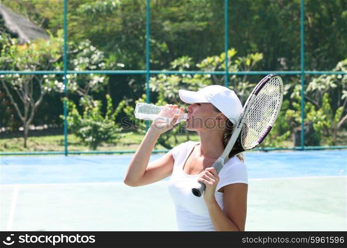 Female tennis player. Female tennis player on court drinking water