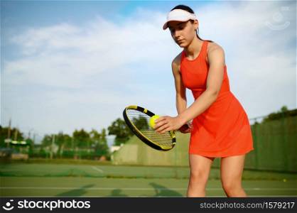 Female tennis player with racket prepares to hit the ball on outdoor court. Active healthy lifestyle, sport game competition, fitness training with racquet. Female tennis player prepares to hit the ball
