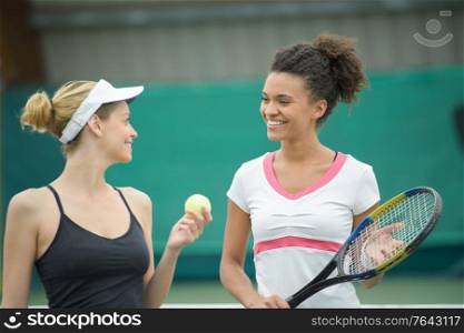 female tennis players talking at a clay court