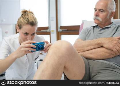 female therapist taking a picture of a mans leg