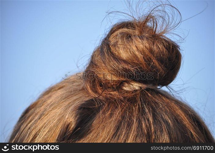 female tied hair with copy space. Female tied gathered up hair over blue sky with copy space