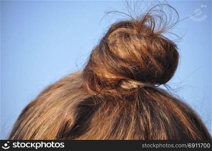 female tied hair with copy space. Female tied gathered up hair over blue sky with copy space