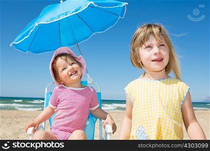 Female toddler and sister looking up from beach