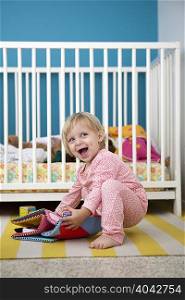 Female toddler playing with textile picture book in bedroom
