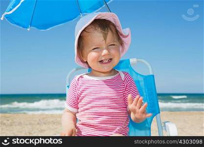 Female toddler wearing sunhat on beach chair