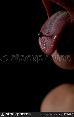 female tongue with piercing on a black background. the girl stuck out her pierced tongue