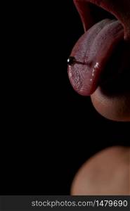 female tongue with piercing on a black background. the girl stuck out her pierced tongue