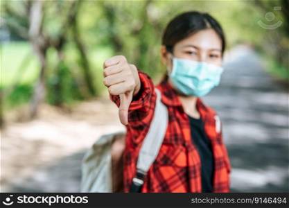 Female tourist carrying a backpack and thumbs down on the road.