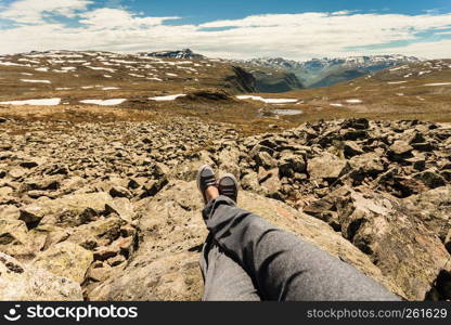 Female tourist relaxing on nature. Human legs and mountains landscape at summer in Norway. Tourism vacation and travel.. Human legs and mountains landscape in Norway.