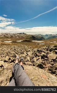 Female tourist relaxing on nature. Human legs and mountains landscape at summer in Norway. Tourism vacation and travel.. Human legs and mountains landscape in Norway.