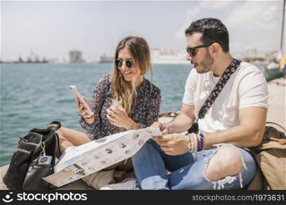 female tourist showing her boyfriend cell phone sitting jetty