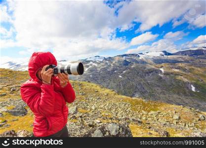 Female tourist taking photo with camera, enjoying mountains landscape from Dalsnibba area in Norway.. Tourist taking photo fin norwegian mountains