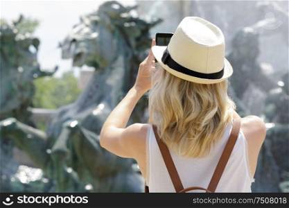female tourist taking picture of a fountain