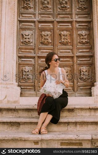 Female tourist with a city map by the church San Francesco d’Assisi in Ostuni, Italy