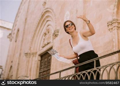 Female tourist with a city map by the church San Francesco d’Assisi in Ostuni, Italy