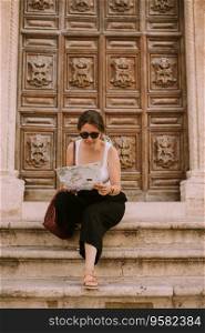 Female tourist with a city map by the church San Francesco d&rsquo;Assisi in Ostuni, Italy