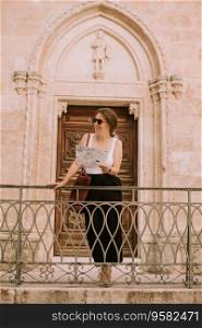 Female tourist with a city map by the church San Francesco d&rsquo;Assisi in Ostuni, Italy